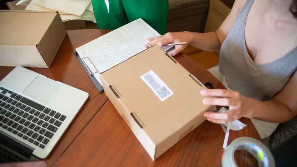 Pequeño negocio gestionando pedidos y operaciones con un portátil y paquetes