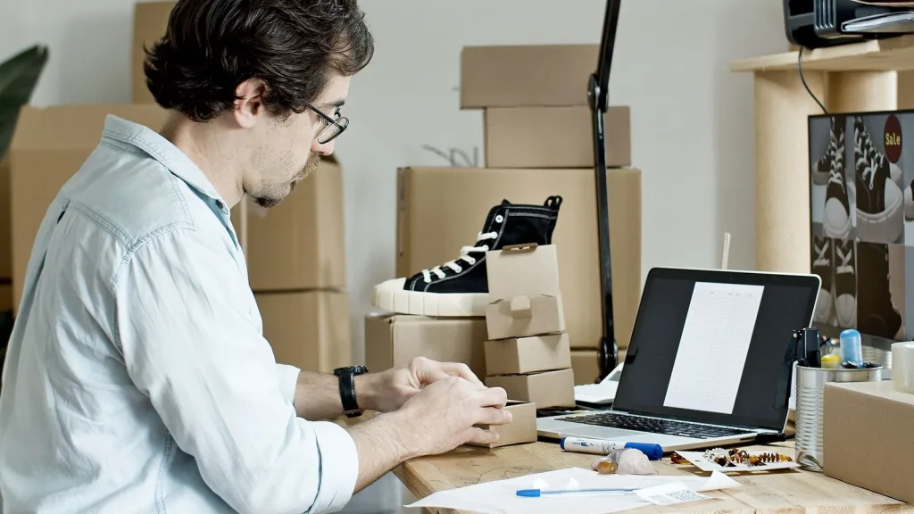 Autónomo preparando pedidos de ecommerce junto a un portátil y productos