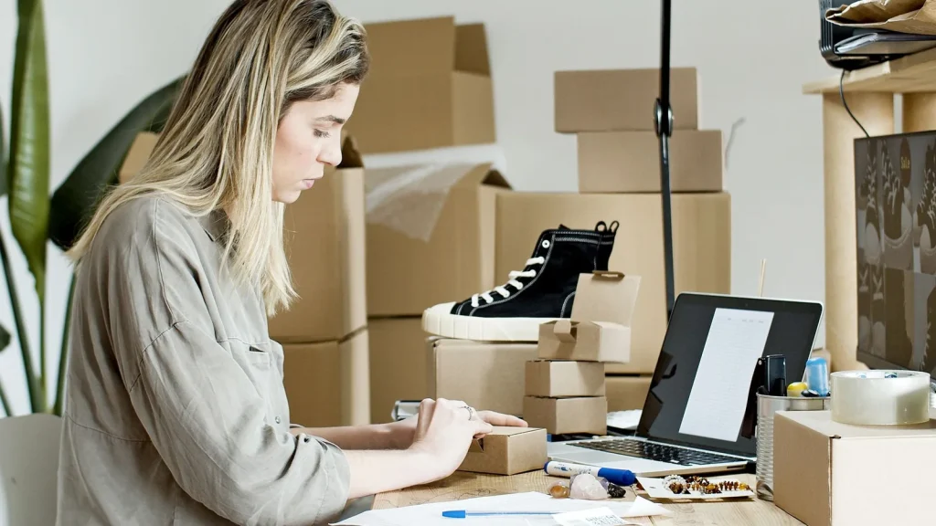 Propietaria de una tienda online preparando pedidos junto a un ordenador